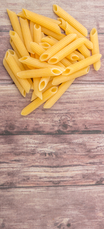 Dried penne regate pasta over wooden backgroundの写真素材