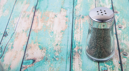 Peppercorn powder in glass condiment shaker over wooden backgroundの写真素材