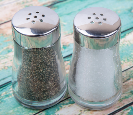 Salt and peppercorn powder in glass condiment shaker over wooden backgroundの写真素材