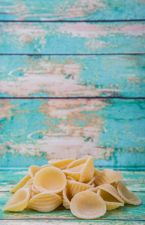 Dried orecchiatte pasta or ear shaped pasta over wooden backgroundの写真素材