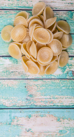 Dried orecchiatte pasta or ear shaped pasta over wooden backgroundの写真素材