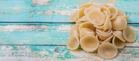 Dried orecchiatte pasta or ear shaped pasta over wooden backgroundの写真素材