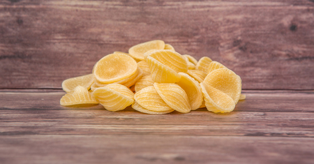 Dried orecchiatte pasta or ear shaped pasta over wooden backgroundの写真素材