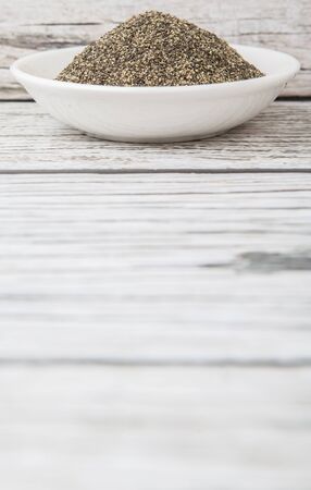 Black pepper powder in white bowl over wooden backgroundの写真素材