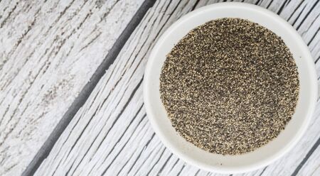 Black pepper powder in white bowl over wooden backgroundの写真素材