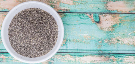 Black pepper powder in white bowl over wooden backgroundの写真素材