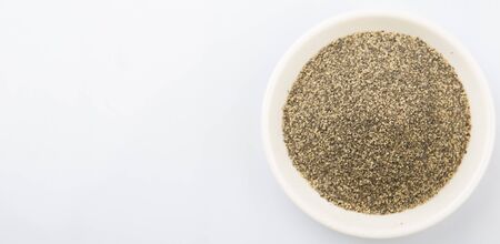 Black pepper powder in white bowl over white backgroundの写真素材