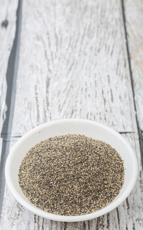 Black pepper powder in white bowl over wooden backgroundの写真素材