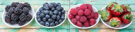 Blackberry, blueberry, strawberry and raspberry in wooden bowl over wooden background