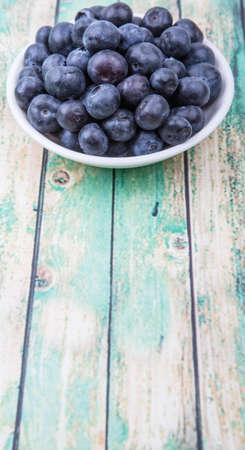 Blueberry fruit in white bowl over wooden backgroundの写真素材