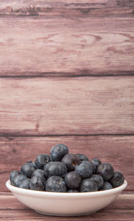 Blueberry fruit in white bowl over wooden backgroundの写真素材