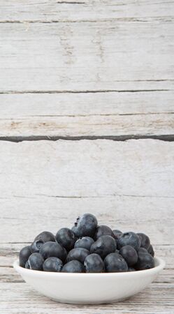 Blueberry fruit in white bowl over wooden backgroundの写真素材