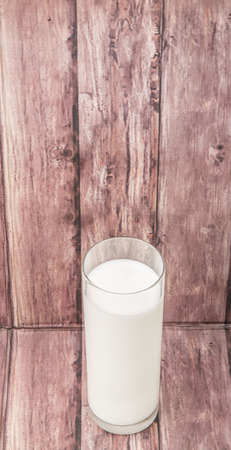 A fresh glass of fresh milk over wooden backgroundの写真素材