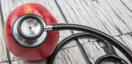 Medical stethoscope and an apple fruit over wooden background.の写真素材