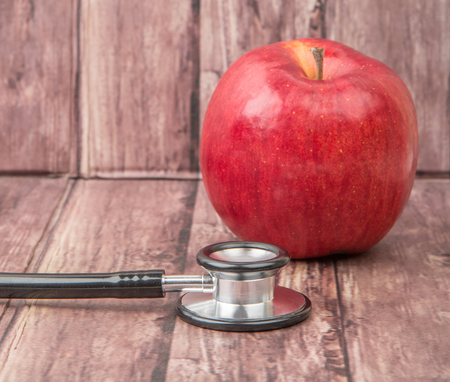 Medical stethoscope and an apple fruit over wooden background.の写真素材