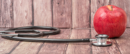 Medical stethoscope and an apple fruit over wooden background.の写真素材