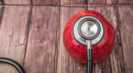 Medical stethoscope and an apple fruit over wooden background.の写真素材