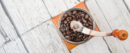 Roasted coffee bean with coffee mill over wooden background