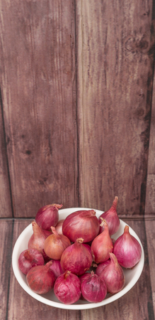 Shallots in white bowl over wooden backgroundの写真素材