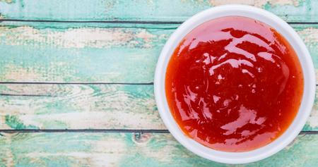 A bowl of thick chili sauce in white bowl over wooden backgroundの写真素材
