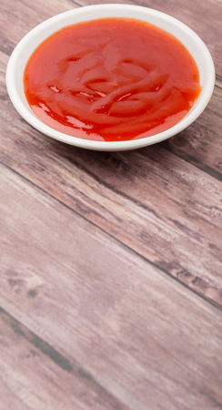 A bowl of thick chili sauce in white bowl over wooden backgroundの写真素材