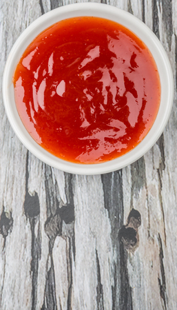 A bowl of thick chili sauce in white bowl over wooden backgroundの写真素材