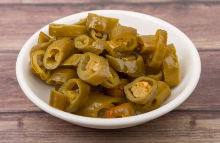 Pickled chili in white bowl over wooden backgroundの写真素材