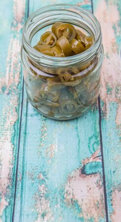Pickled chili in mason jar over wooden background