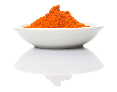 Cayenne pepper powder in white bowl over white backgroundの写真素材