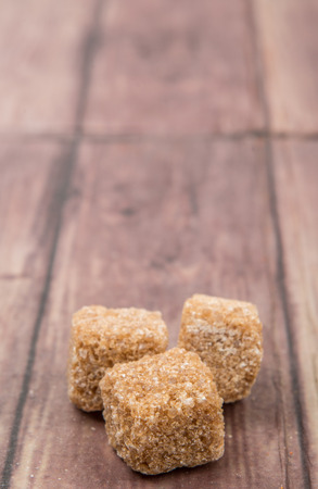 Brown sugarcane sugar cube over wooden backgroundの写真素材