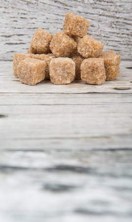 Brown sugarcane sugar cube over wooden backgroundの写真素材