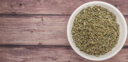 Dried marjoram herbs in white bowl over wooden backgroundの写真素材