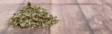 Dried marjoram herbs over wooden background