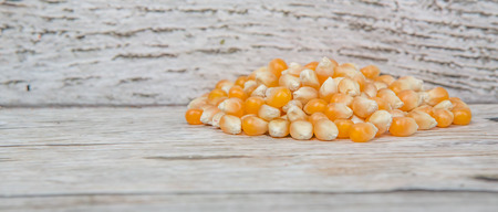 Raw popcorn over wooden background