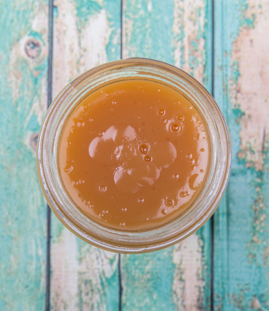 Orange fruit curd in a jar over wooden backgroundの写真素材