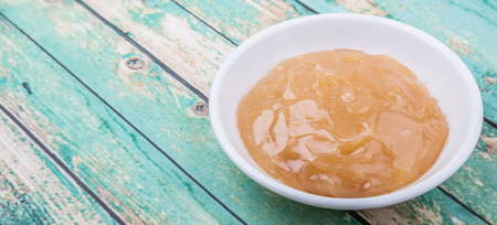 Orange fruit curd in white bowl over wooden backgroundの写真素材