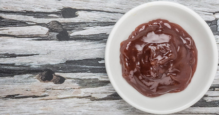 Raspberry fruit curd in white bowl over wooden background