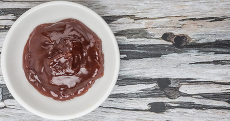 Raspberry fruit curd in white bowl over wooden background