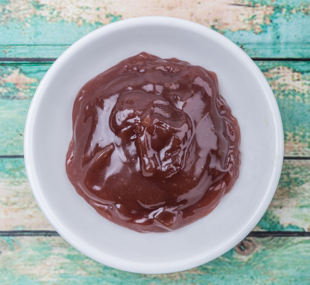Raspberry fruit curd in white bowl over wooden background