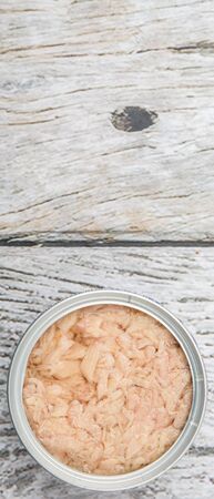 Tuna flakes in tin can over wooden background