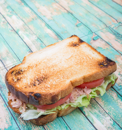 Toasted tuna sandwich with salad and tomato slices over wooden backgroundの写真素材