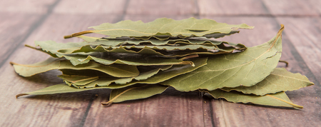 Dried bay leaves herbs over wooden background