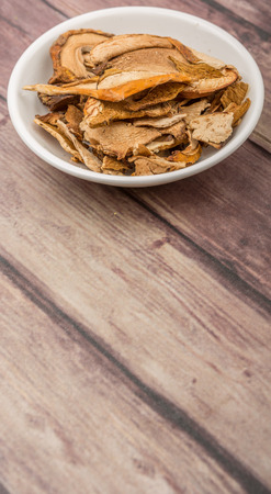 Dried porcini mushroom in a white bowl over wooden backgroundの写真素材