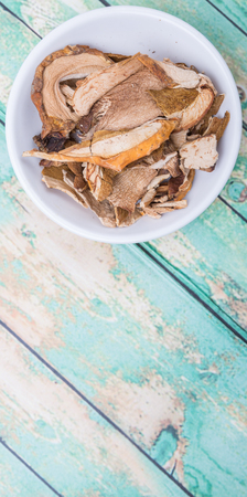 Dried porcini mushroom in a white bowl over wooden backgroundの写真素材