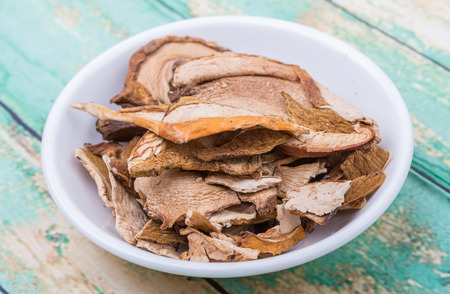 Dried porcini mushroom in a white bowl over wooden backgroundの写真素材
