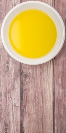 Olive oil in white bowl over wooden backgroundの写真素材