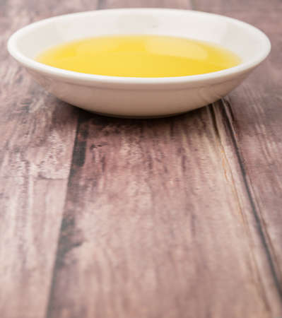Olive oil in white bowl over wooden background