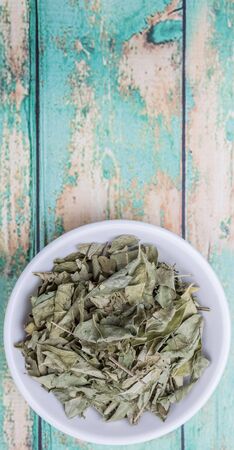 Dried curry leaves in white bowl over wooden backgroundの写真素材