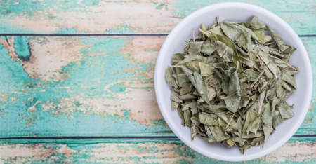 Dried curry leaves in white bowl over wooden backgroundの写真素材
