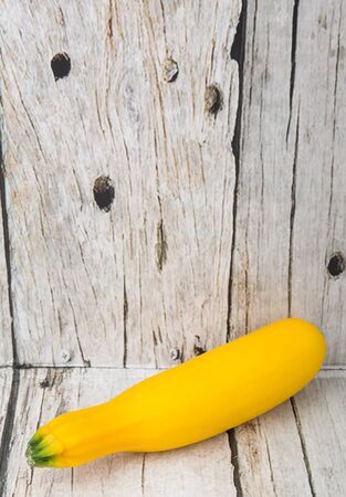 Yellow zucchini over wooden backgroundの写真素材
